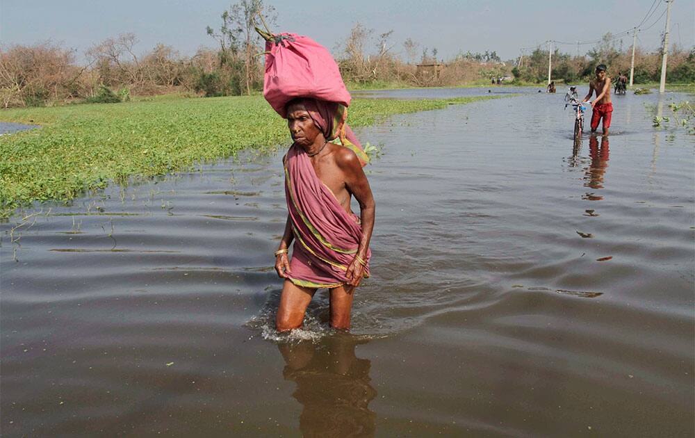 An Indian woman with her belongings wades through a flooded street as she returns to a cyclone hit Pudumpeta village in Ganjam district, Orissa state.