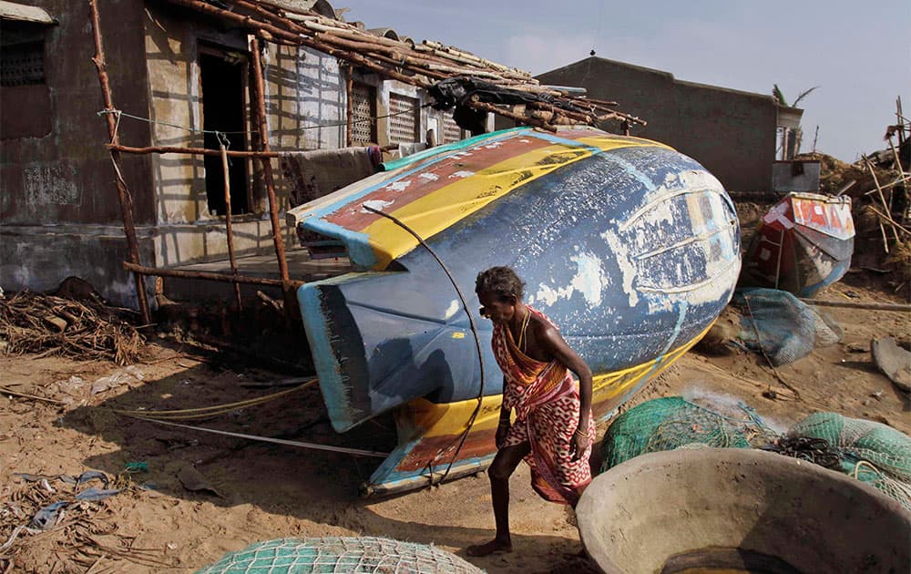 An Indian woman walks near turned boats after returning to cyclone hit Pudumpeta village in Ganjam district, Orissa state.