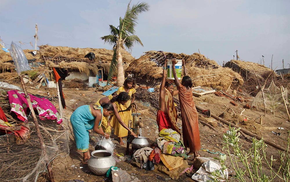 Indian women carry drinking water in containers at a cyclone hit village on the Bay of Bengal coast in Pudumpeta, Ganjam district, Orissa state.