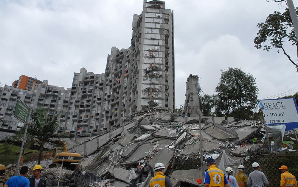 Rescue workers look at the remains of a building that collapsed late Saturday, in Medellin, Colombia.