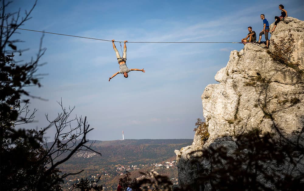 A participant balances on a stretched belt during a slackline event organized by the Outdoor Inhales group at the Tunderszikla rock in Budapest, Hungary.