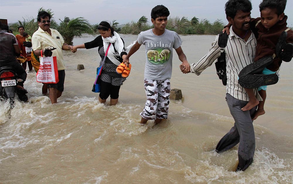 People hold each others` hands and cross a water logged road as they return to their respective villages near Gopalpur, Orissa state.