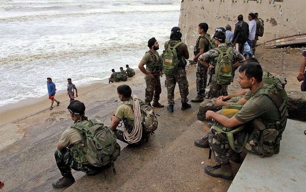 Members of Indian Air Force wait for weather to clear up at a sea shore after the Cyclone Phailin, in Gopalpur, in the eastern Indian state of Orissa.