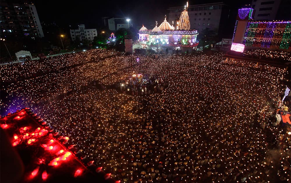 Indian devotees hold earthen lamps and candles as they take part in the Maha Aarti ritual at Hindu deity Umiya Mata temple on the eighth night of Navratri in Surat.