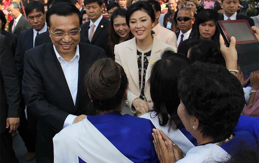 Visiting Chinese Prime Minister Li Keqiang, left, and his Thai counterpart Yingluck Shinawatra, center, are greeted by villagers during their tour of a local products center in Chiang Mai province, northern Thailand.