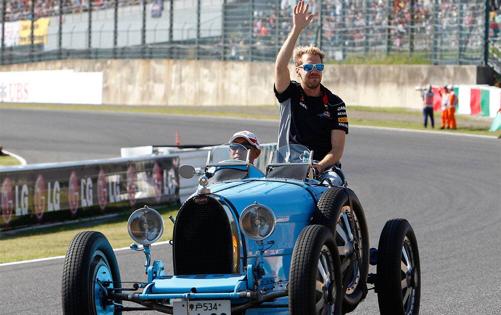 Red Bull driver Sebastian Vettel of Germany waves on a classic car during the drivers` parade prior to the Japanese Formula One Grand Prix at the Suzuka circuit in Suzuka, Japan.