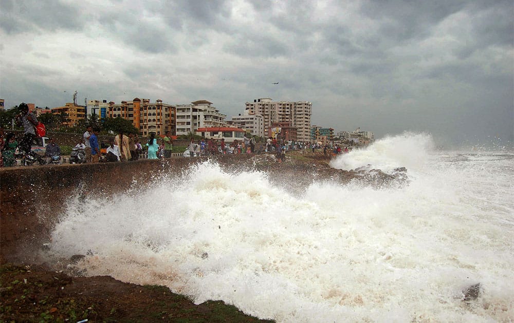 People watch high tide waves as they stand at the Bay of Bengal coast in Vishakhapatnam. Hundreds of thousands of people living along India`s eastern coastline were taking shelter Saturday from a massive, powerful cyclone Phailin that was set to reach land packing destructive winds and heavy rains.