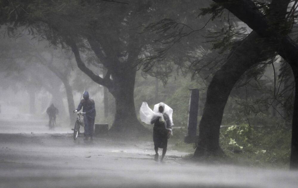 A man covers himself with a plastic sheet as a shield from the rain as he walks to a safer place near Gopalpur junction in Ganjam district about 200 kilometers (125 miles) from the eastern Indian city Bhubaneswar.
