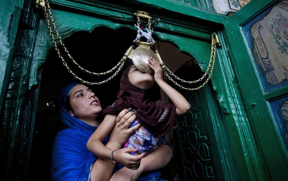An unidentified Kashmiri woman helps her daughter to kiss the religious iron chain at the entrance of the shrine of Shah e Hamdan on the death anniversary of sufi scholar Mir Syed Ali Hamadani in Srinagar.