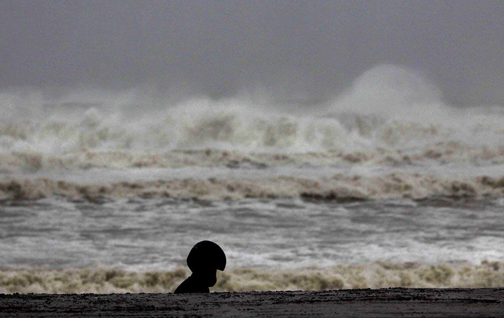 A man in a helmet walks past high waves of the Bay of Bengal at Gopalpur beach in Ganjam district, about 200 kilometers (125 miles) from the eastern Indian city Bhubaneswar.