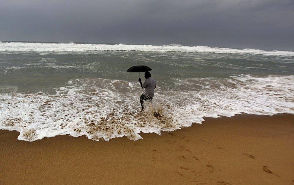 A man holds on to his umbrella as he fishes in high tide waves at Gopalpur beach, in Ganjam district, 215 kilometers (136 miles) away from the eastern Indian city of Bhubaneswar.