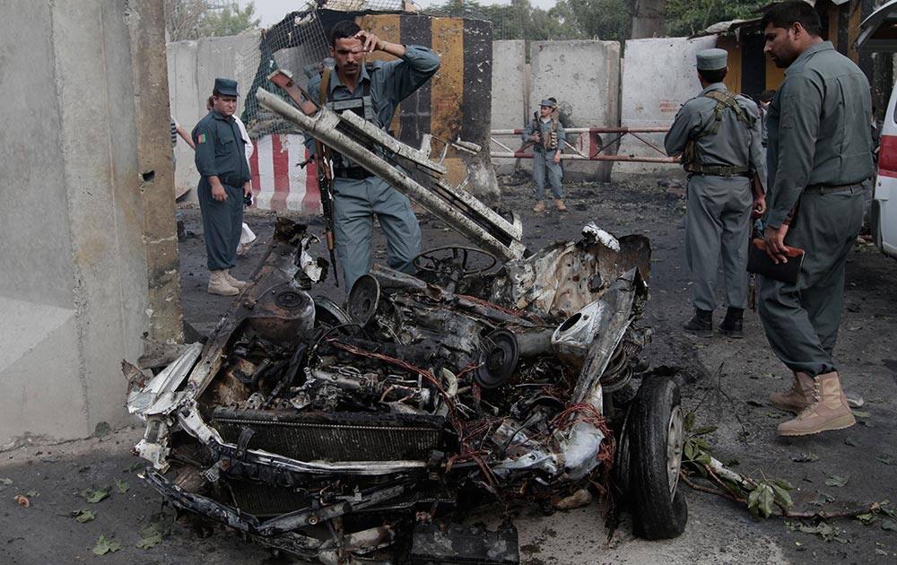 Afghan police examines the remains of a car after a suicide bomber attacked a police headquarters in Jalalabad east of Kabul, Afghanistan.