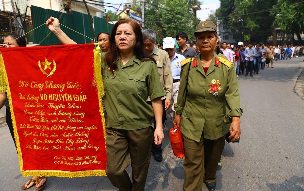 Vu Thi Dieu Huong, a Vietnam War veteran holds a flag with their condolence to the late Gen. Vo Nguyen Giap written as she walks among others to the national funeral house in Hanoi.