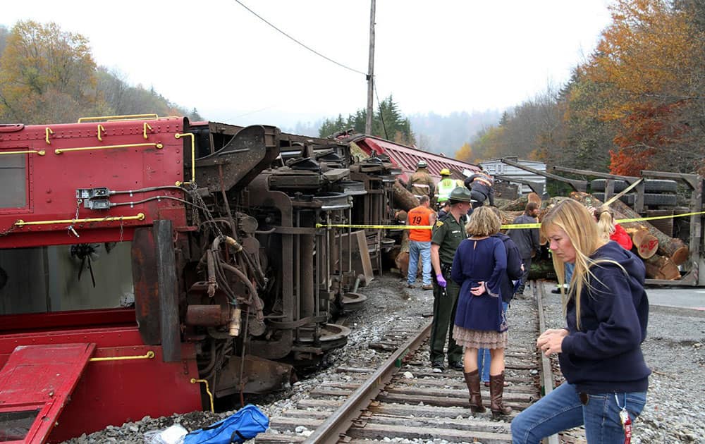 This photo provided by the Pocahontas Times, crews work at the site where a truck carrying logs down Cheat Mountain on US Route 250 crashed into the side of a train taking passengers on a scenic tour in rural Randolph County, W.Va.