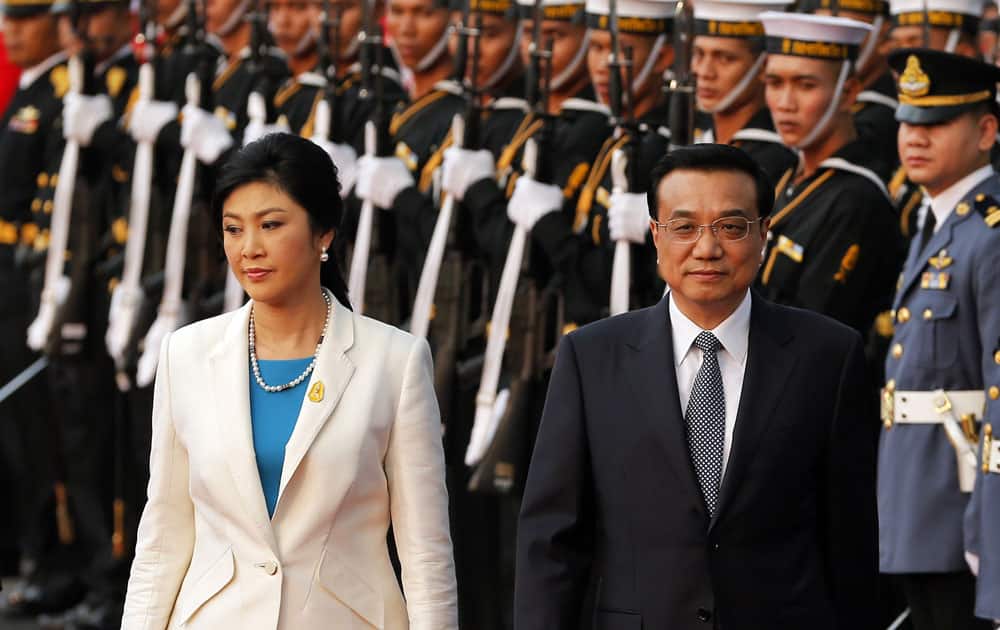Chinese Premier Li Keqian, is escorted by Thailand`s Prime Minister Yingluck Shinawatra as he inspects an honor guard during a welcoming ceremony at the government house in Bangkok.