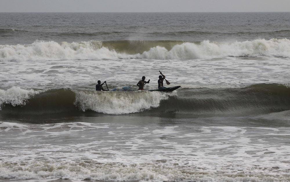 Indian fishermen on a country boat negotiate the waves as they return with their catch on the Bay of Bengal coast at Puri, Odisha state.