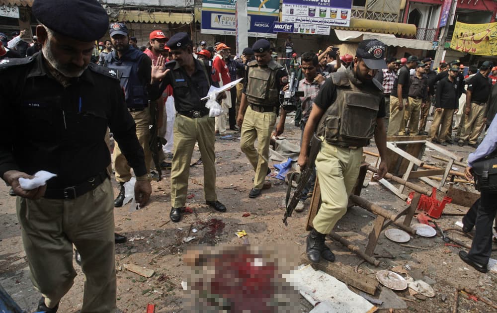 Pakistani police officers check the site of a deadly explosion in a busy market in Lahore, Pakistan.