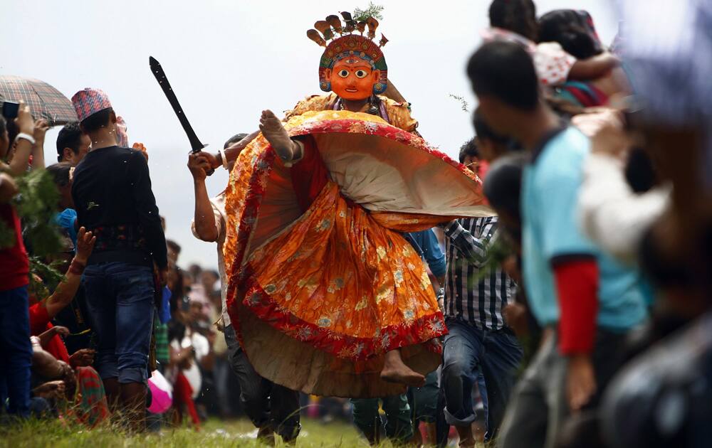 Nepalese devotees carry a dancer wearing a mask of a deity as he performs during Shikali festival in Khokana, Lalitpur, Nepal.