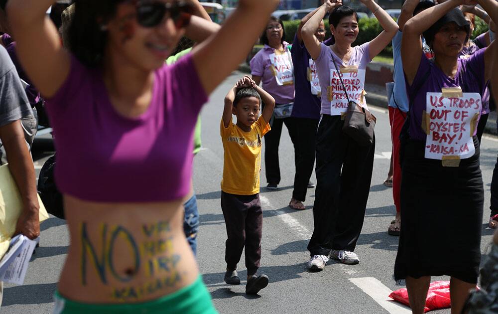 A Filipino boys joins women dancing during a protest near the US Embassy in Manila, Philippines.