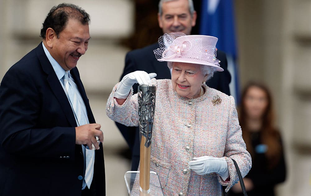 Britain`s Queen Elizabeth II places her message to the Commonwealth Games in the Commonwealth Games Baton, as Prince Imran of Malaysia, President of the Commonwealth Games Federation, looks on during its launch ceremony at the Buckingham Palace in London.