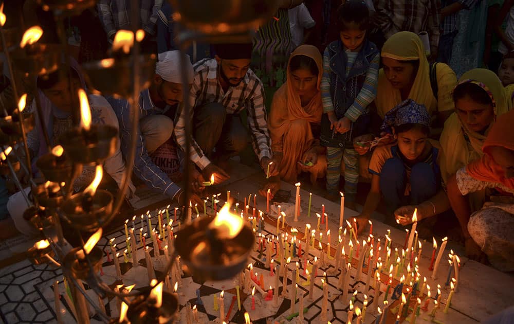 Sikh devotees light candles and lamps at the Golden Temple, Sikh`s holiest shrine, illuminated on the occasion of the birth anniversary celebrations of Guru Ram Das in Amritsar.
