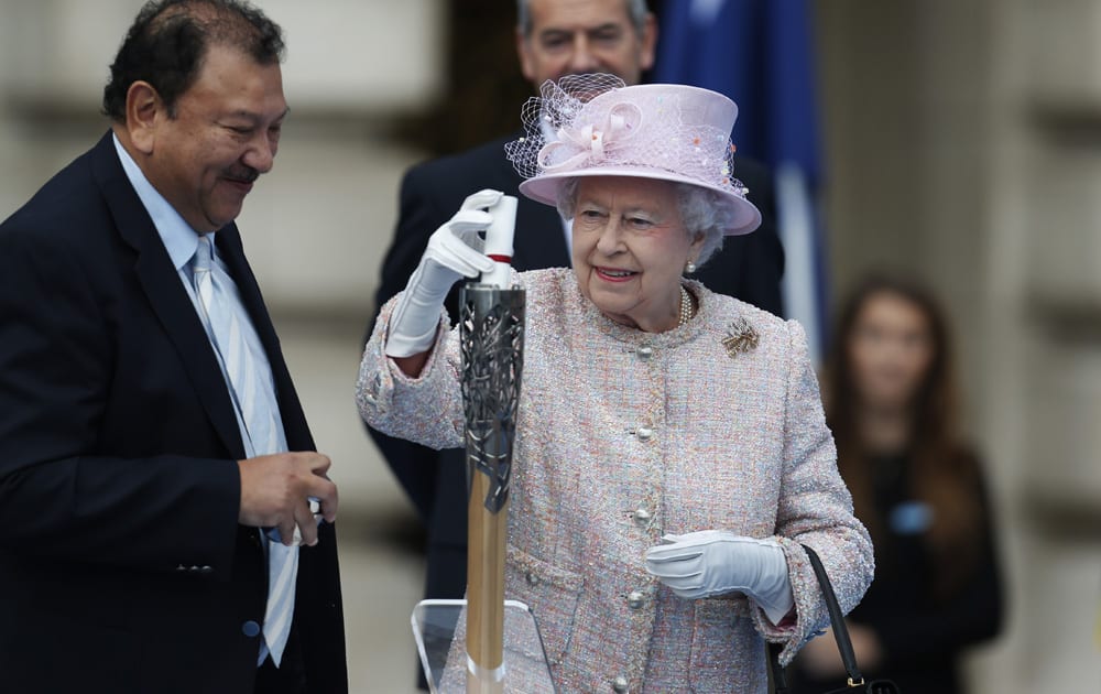 Britain`s Queen Elizabeth II places her message to the Commonwealth Games in the Commonwealth Games Baton, during its launch ceremony at the Buckingham Palace in London.