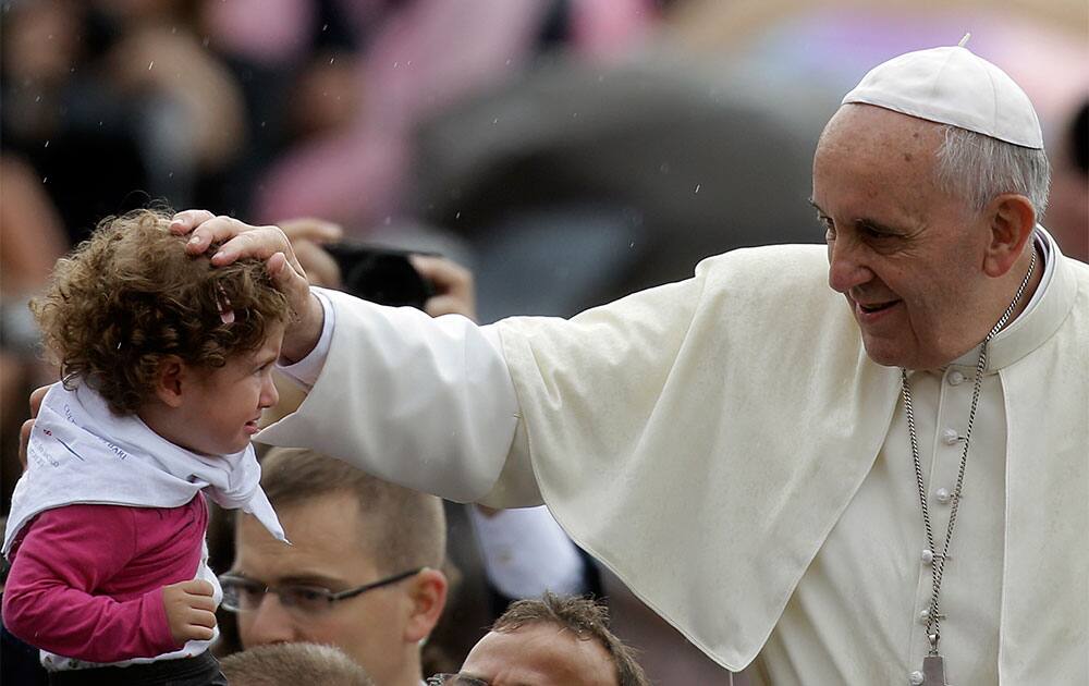 Pope Francis blesses a child during the weekly general audience in St. Peter`s Square, at the Vatican.
