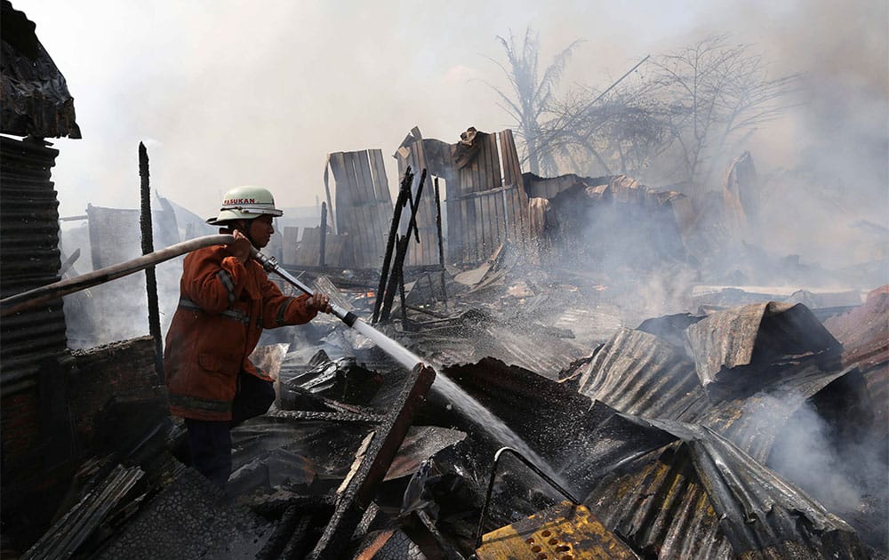 An Indonesian firefighter extinguishes a fire at an illegal housing complex, constructed on land belonging to a company, in Jakarta.