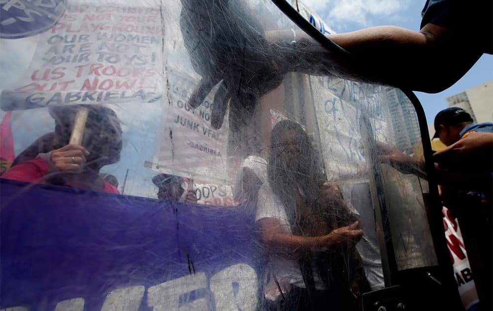 Protesters display placards as they hold a rally near the US Embassy in Manila, Philippines after being prevented by police from getting closer to the Embassy to protest the forthcoming visit of US State Secretary John Kerry in place of US President Barack Obama who canceled his entire trip to Asia.
