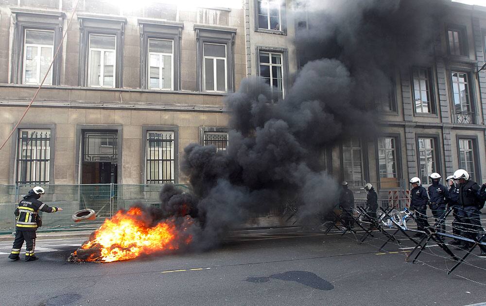 A firefighter throws a tyre on a fire as police block the road towards the Belgian Parliament during a protest in Brussels. As the government meets on next year`s budget, protesting firefighters ask for extra money.