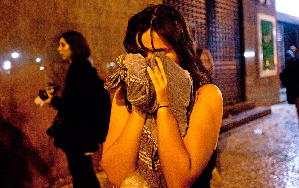 A woman covers from tear gas fired by police near the Cinelandia square after a march in support of teachers on strike in Rio de Janeiro, Brazil.