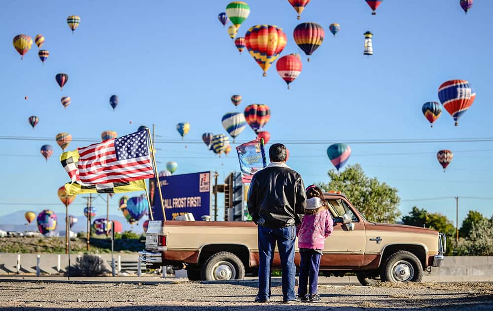 Spectators stand on El Pueblo Road near Paseo del Norte in Albuquerque, N.M. to watch the first mass ascension of the annual Albuquerque International Balloon Fiesta.