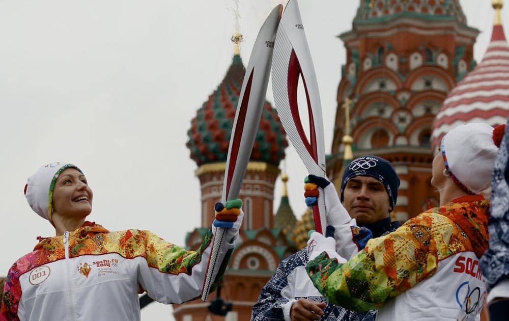 Russian Olympic gold medalists, synchronized swimmer Anastasya Davydova and former artistic gymnast Svetlana Khorkina, join their torches during a relay of the Olympic flame in Moscow.