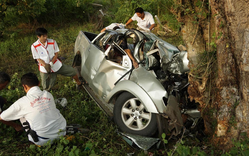 Workers examine the wreckage of a pickup truck at slammed into a tree in Ban Dan district in Buriram province, 300 kilometers (190 miles) northeast of Bangkok.