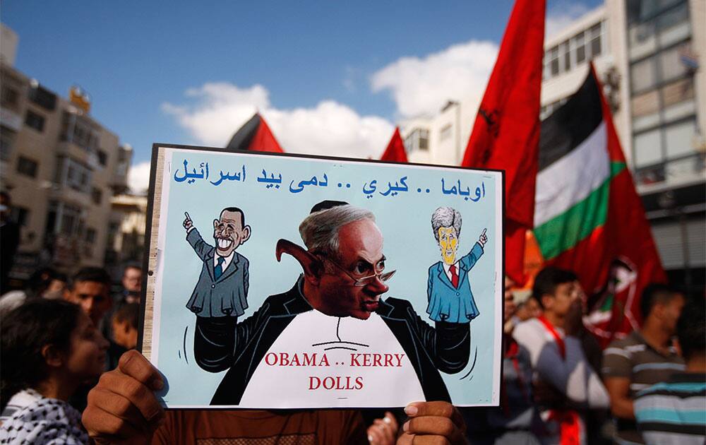 A Palestinian protester holds up a poster with a caricature of US Secretary of State John Kerry during a protest against the resuming of the peace talks with Israel, in the West Bank city of Ramallah.