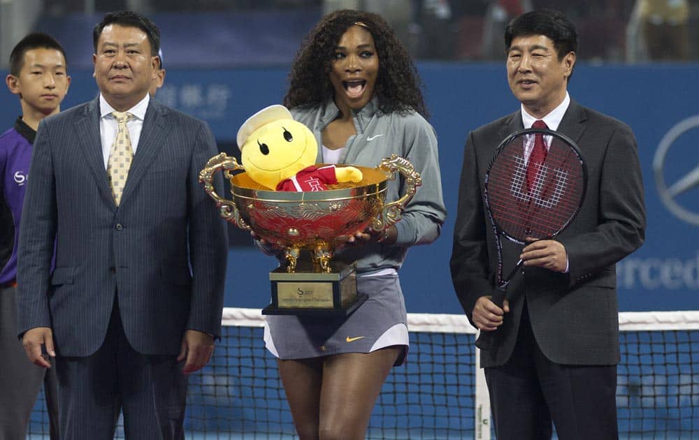 Serena Williams of US, reacts with her winning trophy as she poses with Chinese officials after the final of the China Open tennis tournament at the National Tennis Stadium in Beijing.