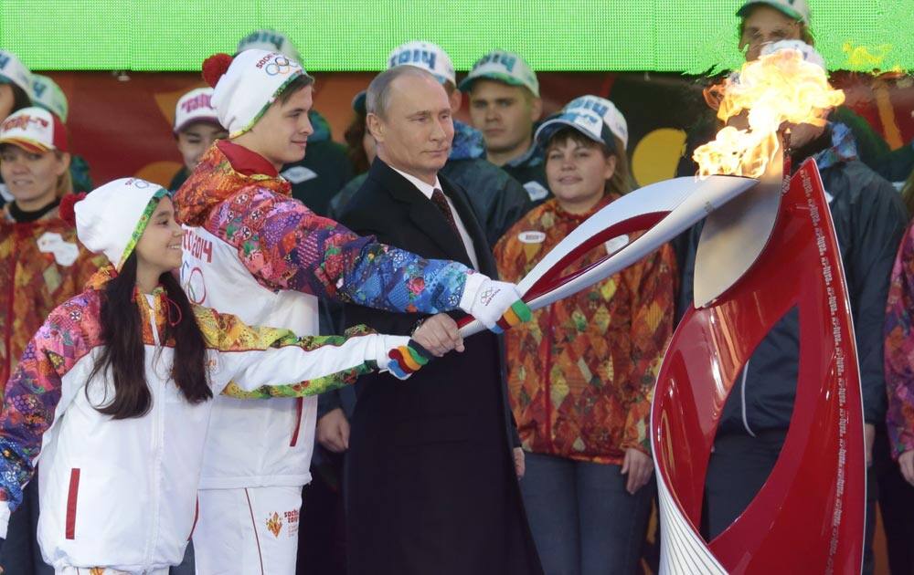 Russian President Vladimir Putin, a girl and a boy light an Olympic flame with a torch at Moscow`s Red Square.