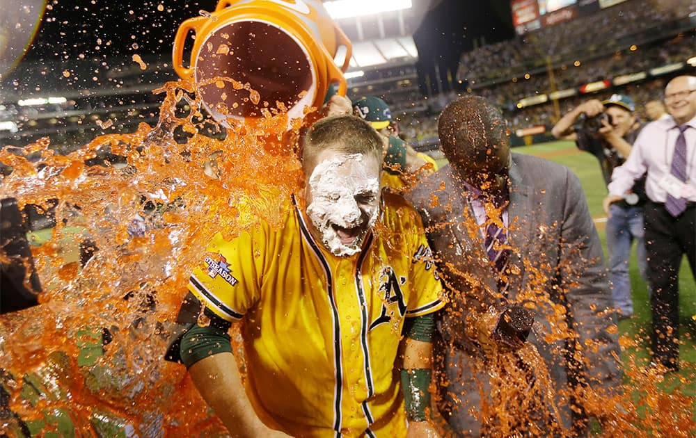 Oakland Athletics` Stephen Vogt gets a Gatorade shower after making the game-winning hit to beat the Detroit Tigers 1-0 in Game 2 of the American League baseball Division Series in Oakland, Calif.