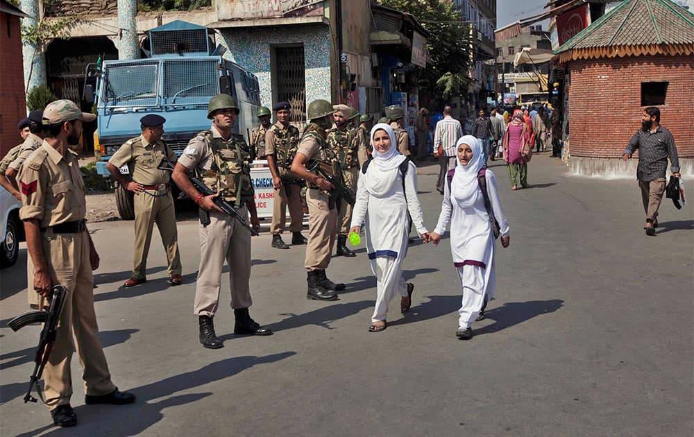 Kashmiri school children walk past Indian paramilitary soldiers as they stand guard in Srinagar.