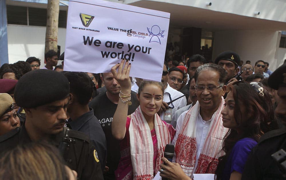 Miss Universe Olivia Culpo, holds a placard as she stands with Assam state Chief Minister Tarun Gogoi, during a campaign