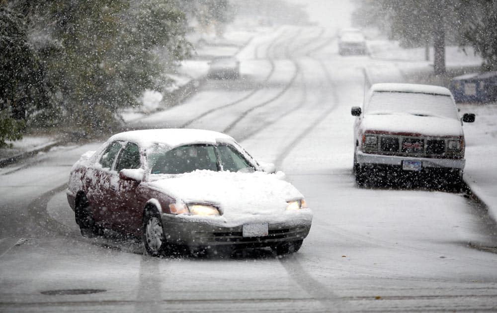 Motorists make their way down 6th Street during a snowstorm, in Rapid City, S.D. Blizzards rolled into parts of Wyoming and South Dakota, bringing the states to an unseasonably early wintery standstill by closing highways and schools.