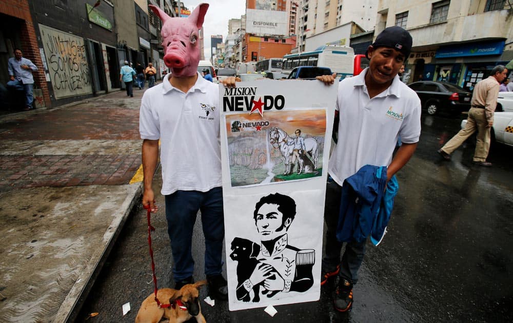 Two men, one wearing a pig head mask in protest against the slaughter of pigs for human consumption, hold a poster demonstrating Venezuelan hero Simon Bolivar as an animal lover, during a demonstration marking World Animal Day in Caracas.