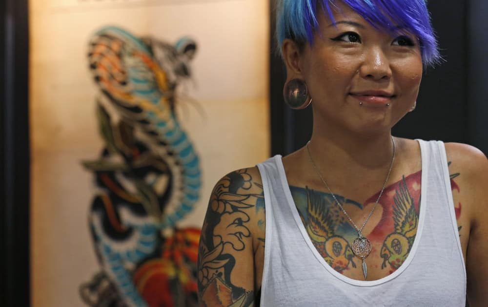 A woman with tattooed body stands at a design booth during the first International Hong Kong China Tattoo Convention in Hong Kong.