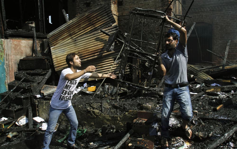Kashmiri school staff members carry damaged furniture after a fire broke out in a school building in Srinagar.