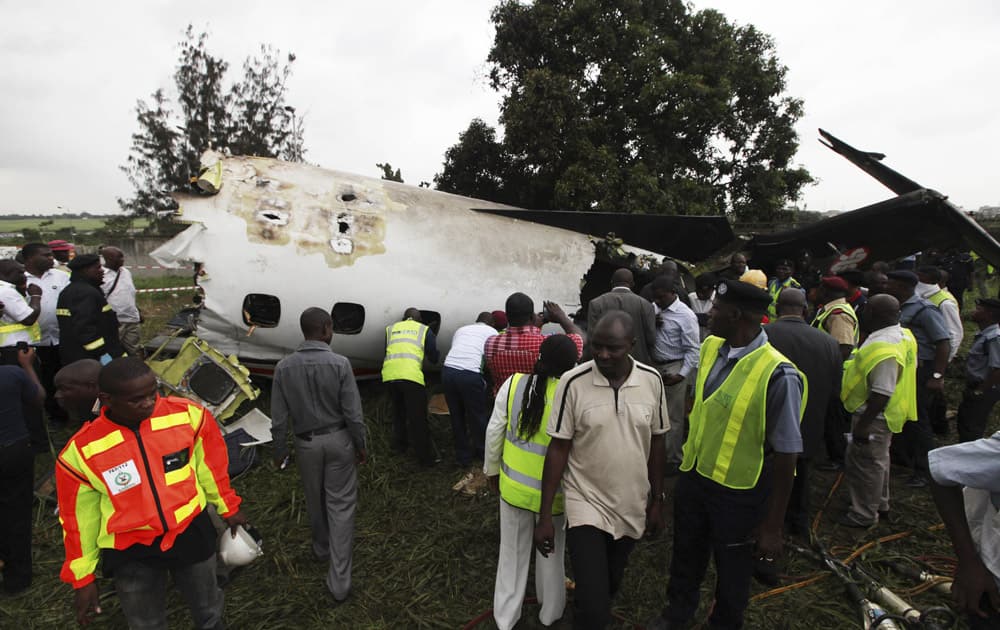 Rescue workers gather around the wreckage of a charter passenger jet which crashed soon after take off from Lagos airport, Nigeria.