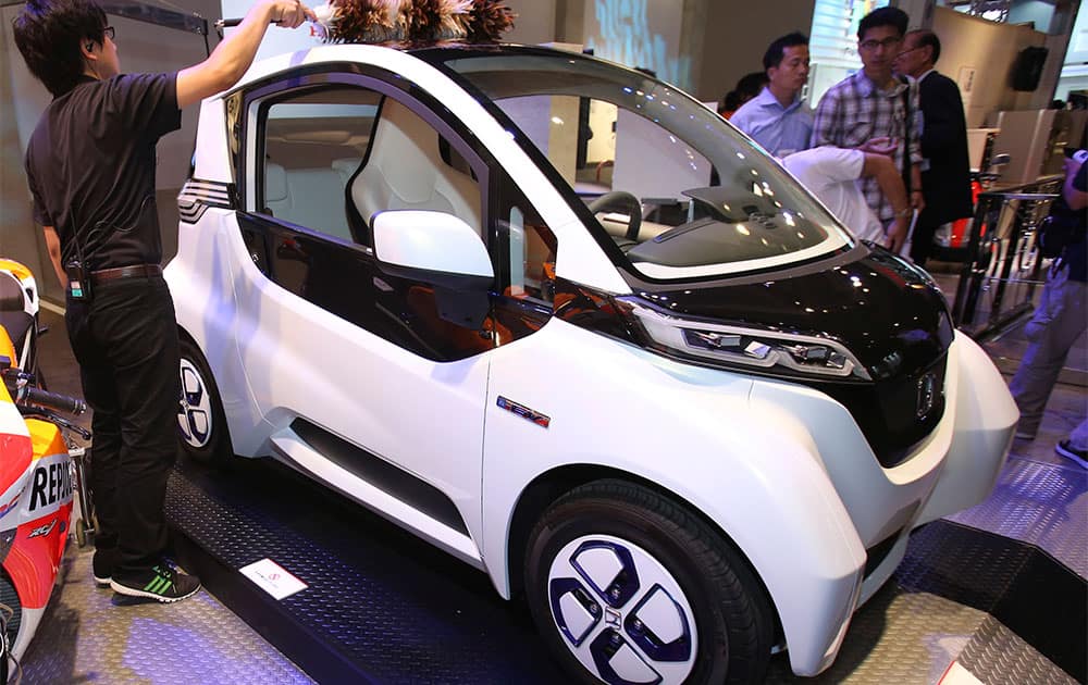 An event staff cleans a Honda Motor Co.`s Micro Commuter prototype electric vehicle during the annual CEATEC advanced technologies exhibition in Chiba near Tokyo.