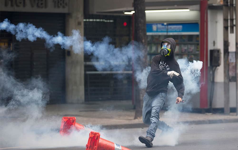 A protestor throws a tear gas toward police officers during a protest outside the City Council in Rio de Janeiro, Brazil.