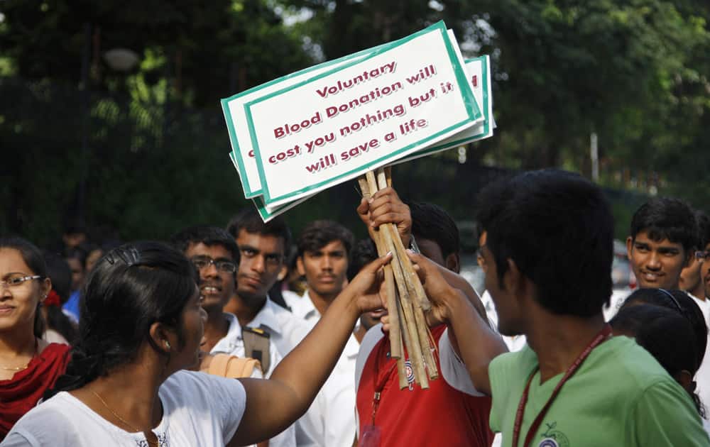 A student hands out placards to participants of a rally observing the National Voluntary Blood Donation Day in Hyderabad.