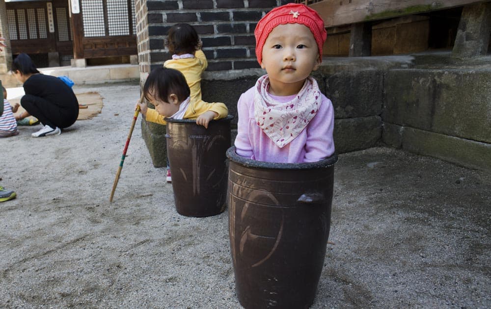 Jung Ha-yoon, 2, appears to be stuck inside a ceramic container while playing with other children at the traditional sports square during the