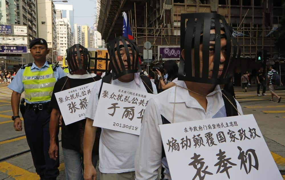 Pro-democracy protesters wear cages and cardboards written the name of jailed Chinese dissidents as they march to Government office during the China`s National Day in Hong Kong.
